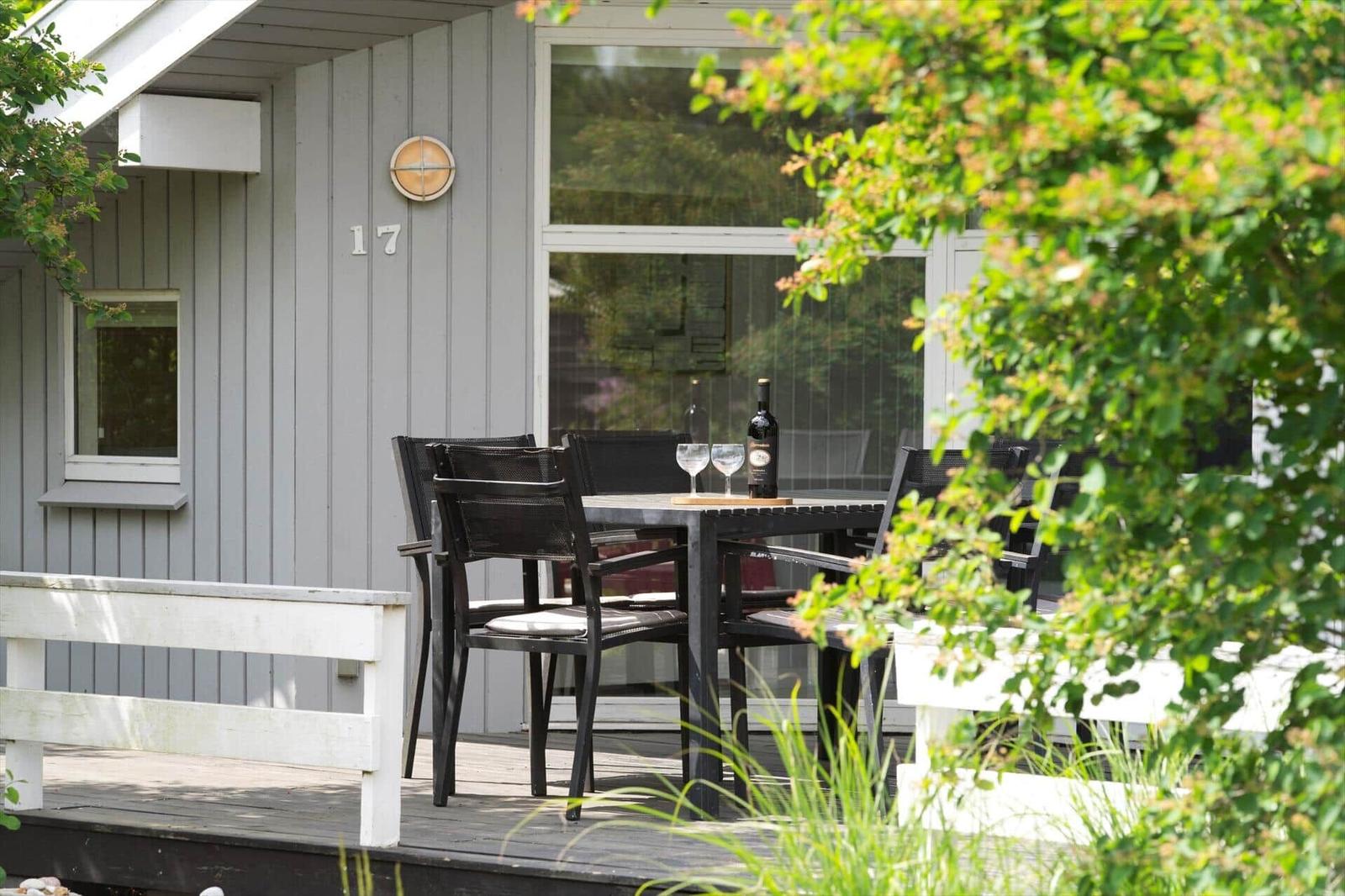 Terrasse mit Tisch, Stühlen und Weinflasche vor einem Haus mit Nummer 17.