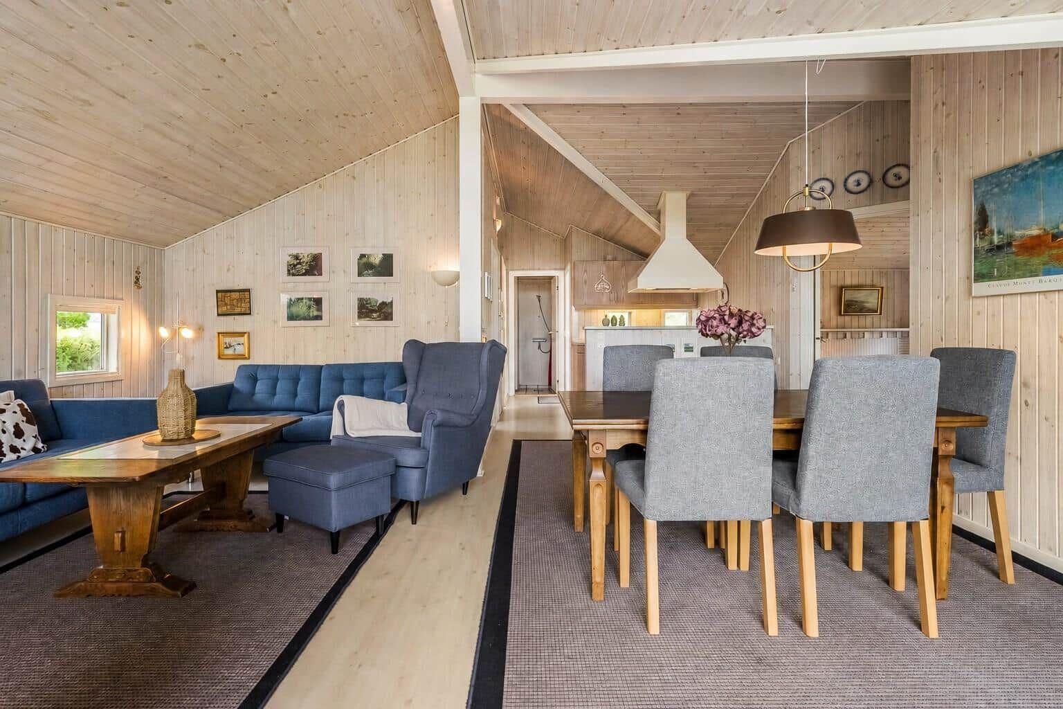 Wohn- und Essbereich mit Holzwand, Sofa und Esstisch mit Stühlen.