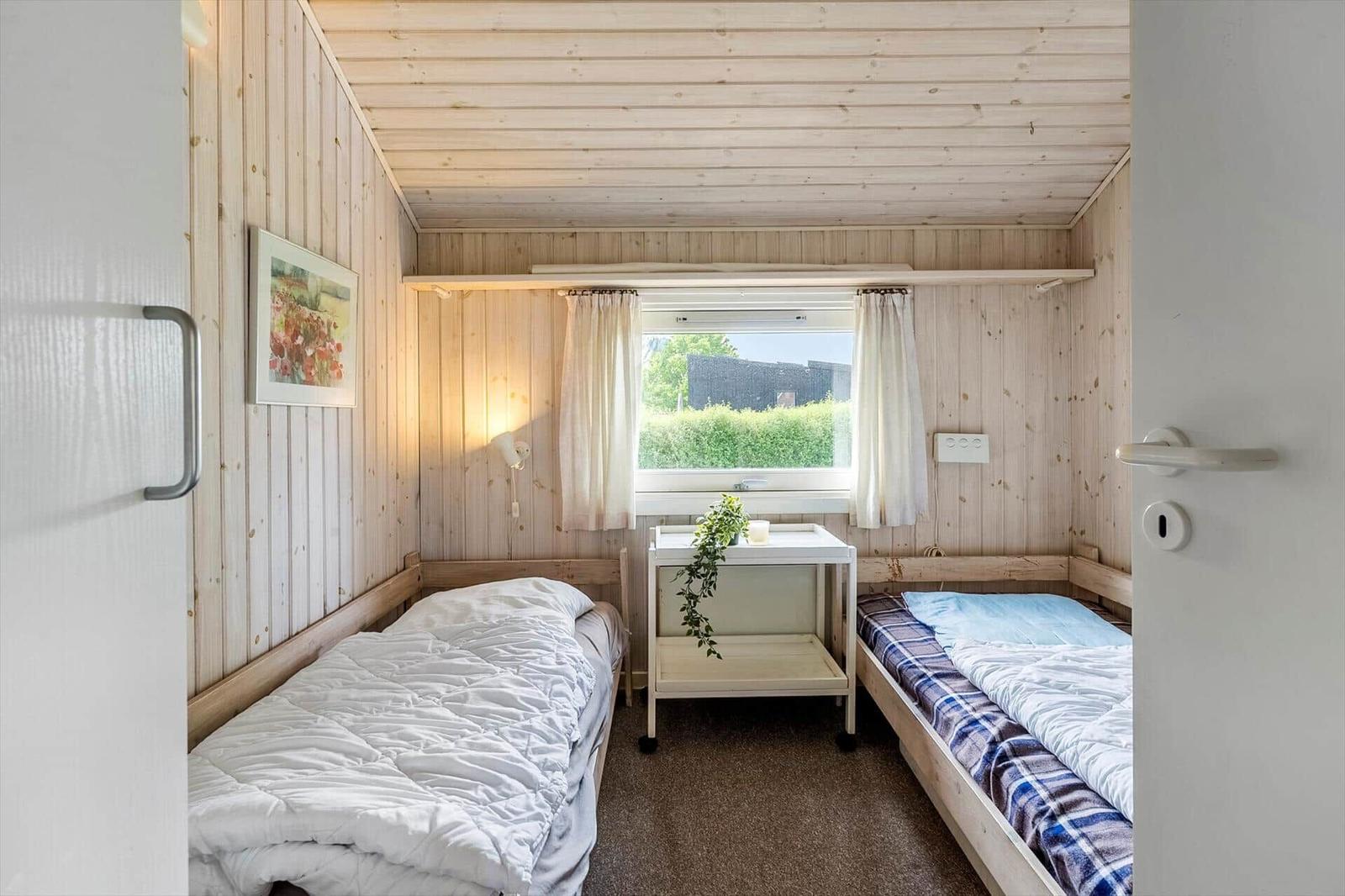 Zwei Betten in einem Raum mit Holzwänden und einem Fenster.