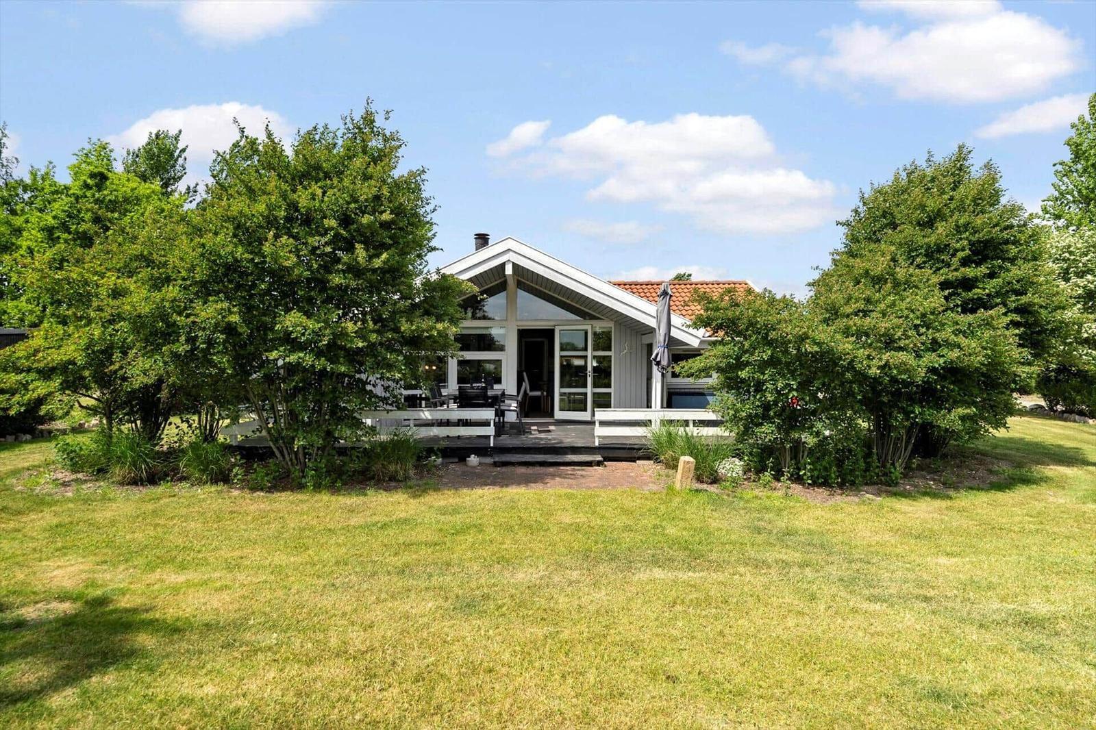 Ein Haus mit Terrasse und Garten unter blauem Himmel.