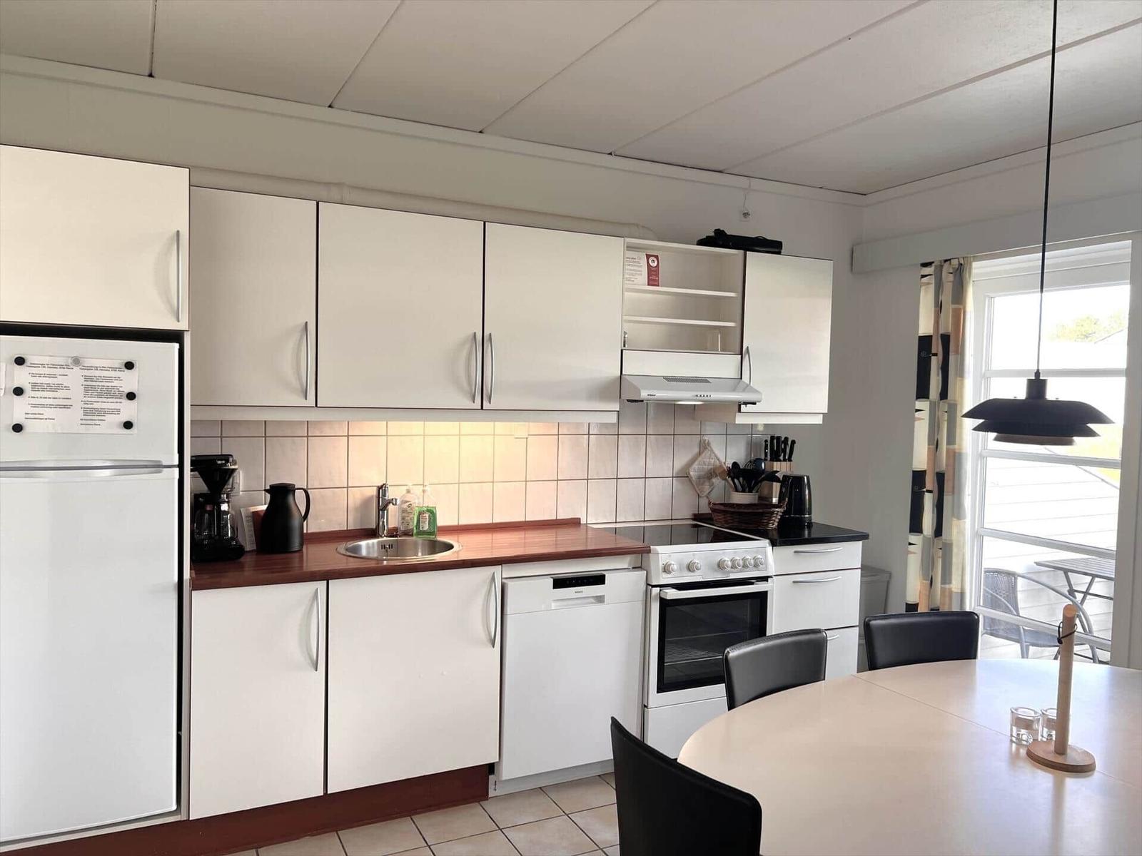 Kitchen with white cabinets, stainless steel sink, and round table with chairs.
