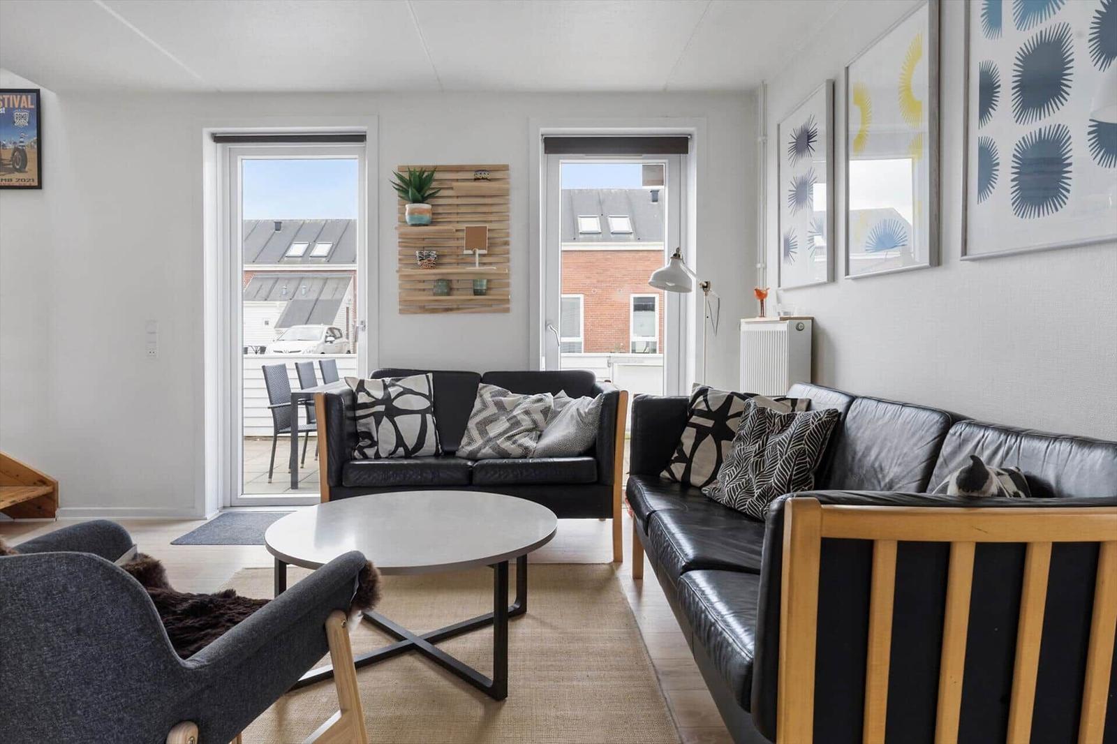 Wohnzimmer mit zwei Sofas, runden Tisch und Fenstern zum Balkon.