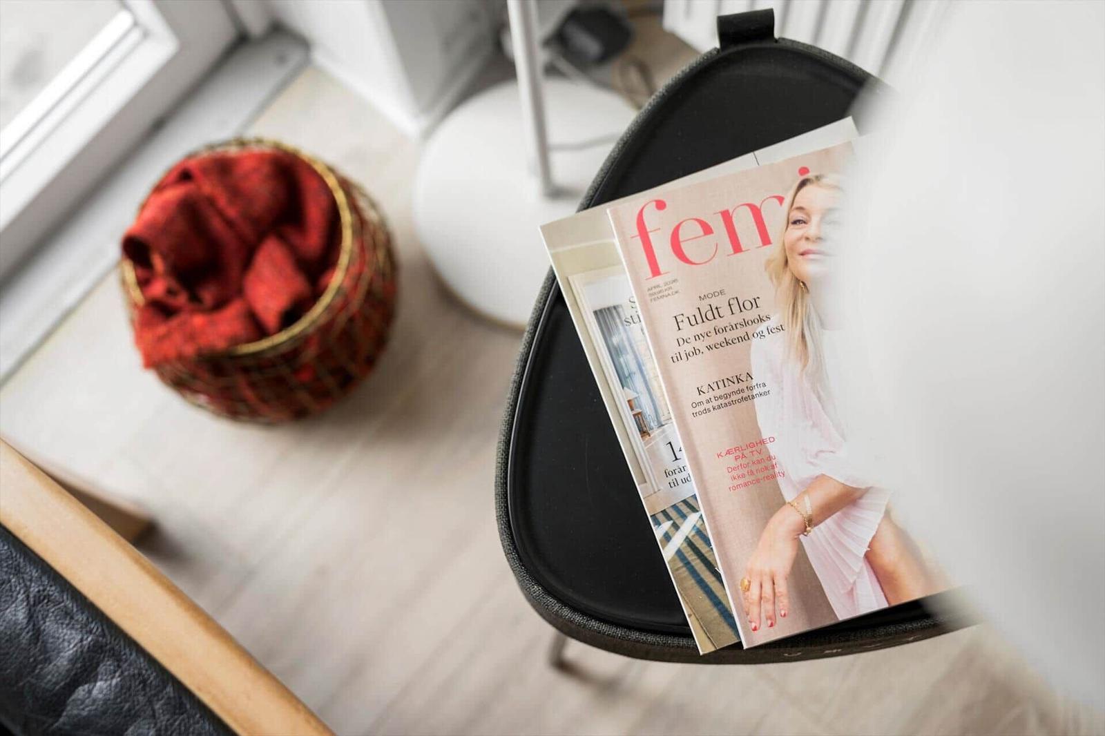Magazine auf einem schwarzen Stuhl neben einem Korb mit rotem Stoff.