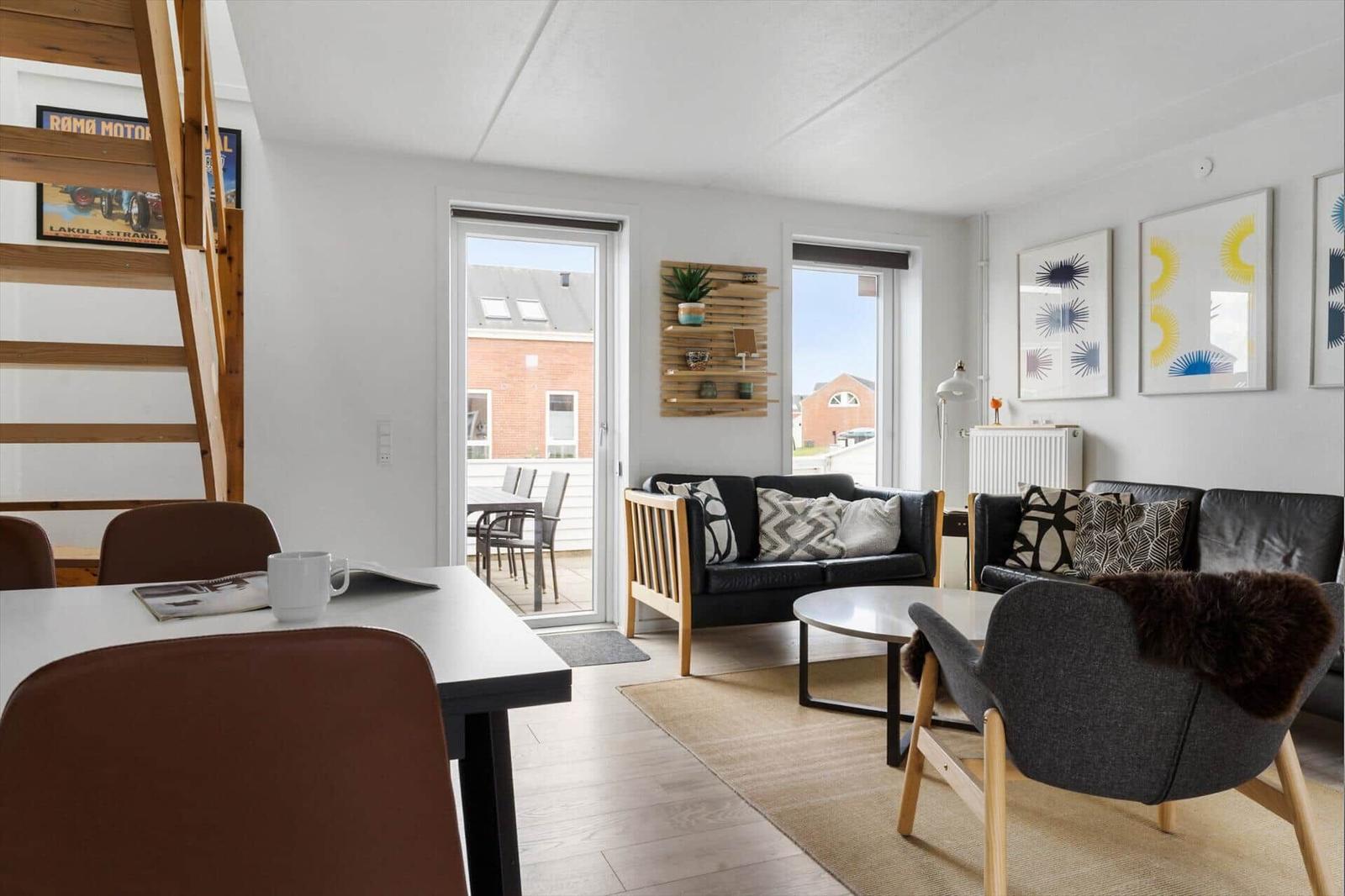 Wohn- und Essbereich mit Sofa, Stuhl und Tisch. Durchgänge zu Balkon und Terrasse.
