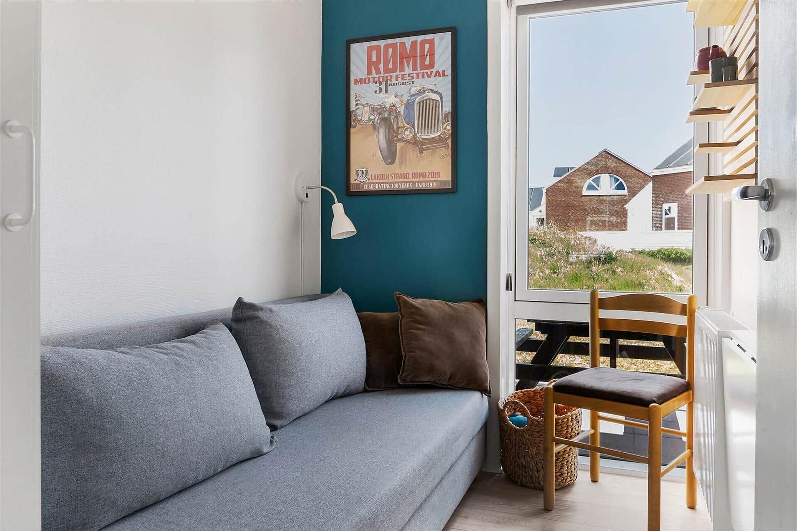 Ein Sofa mit Kissen, Wandposter und Sicht auf einen Außenbereich.