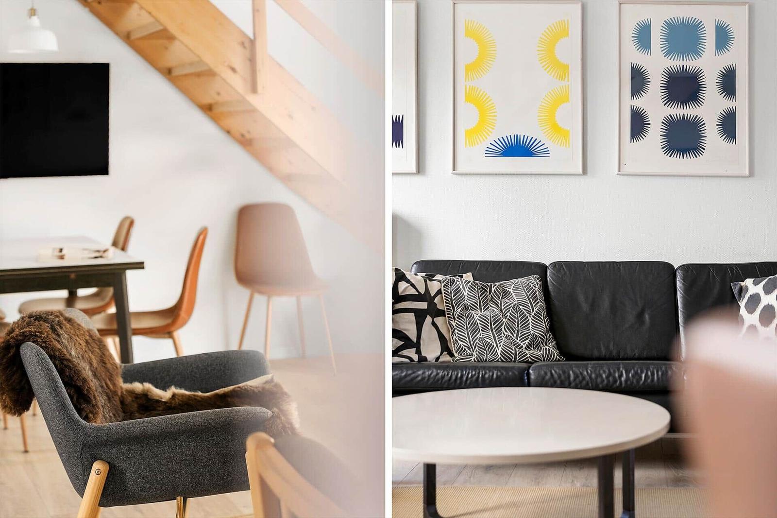Wohnzimmer mit schwarzer Ledercouch, runden Tisch und Wandbildern. Links: Essbereich mit Holztisch und Stühlen.