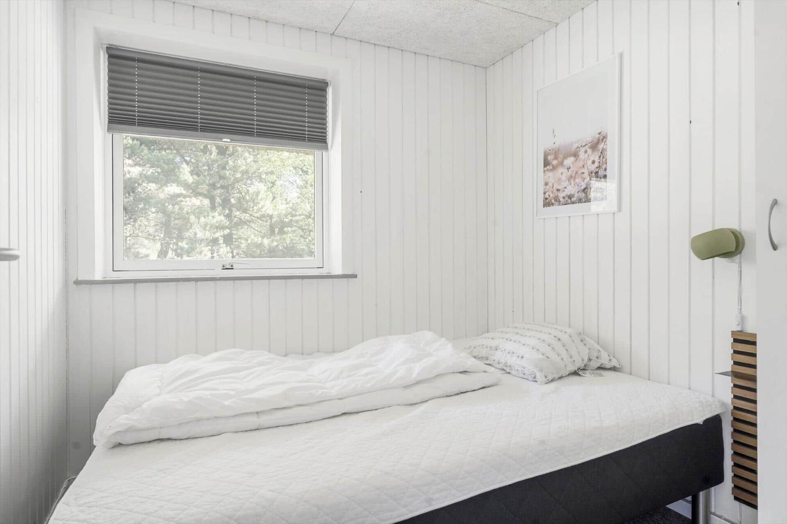 Schlafzimmer mit Bett, Fenster und Wandbild.