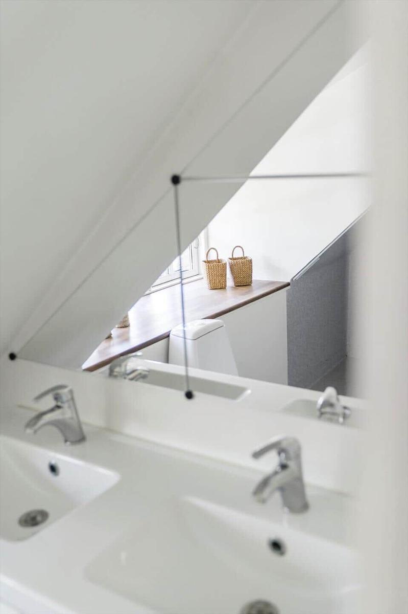 Dusche mit Spiegel und Fenster, zwei Körbe auf Holzbank