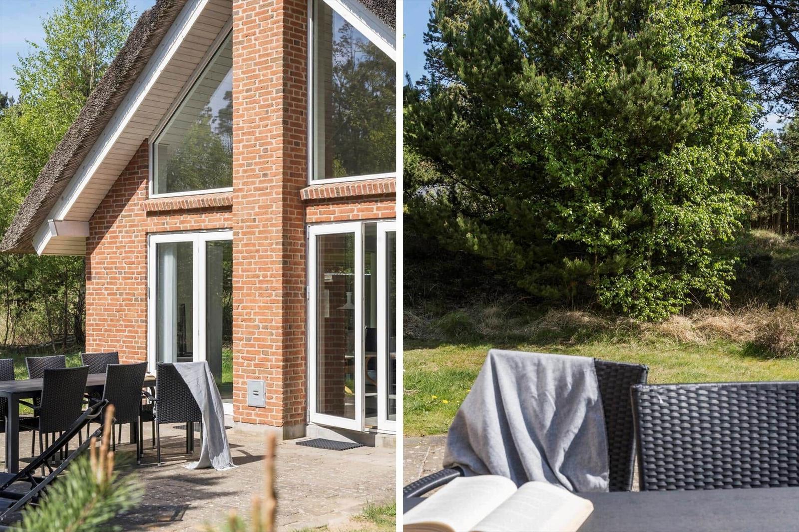 Haus mit Terrasse, Garten und Bäumen. Außentisch mit Stühlen und offenem Buch.