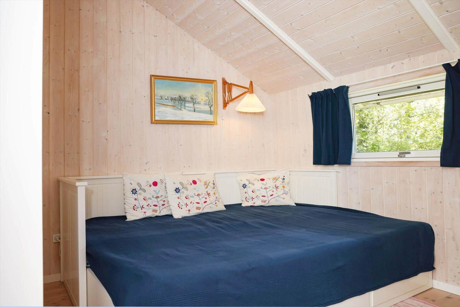 Bedroom with bed, wall picture, and window with view of green.