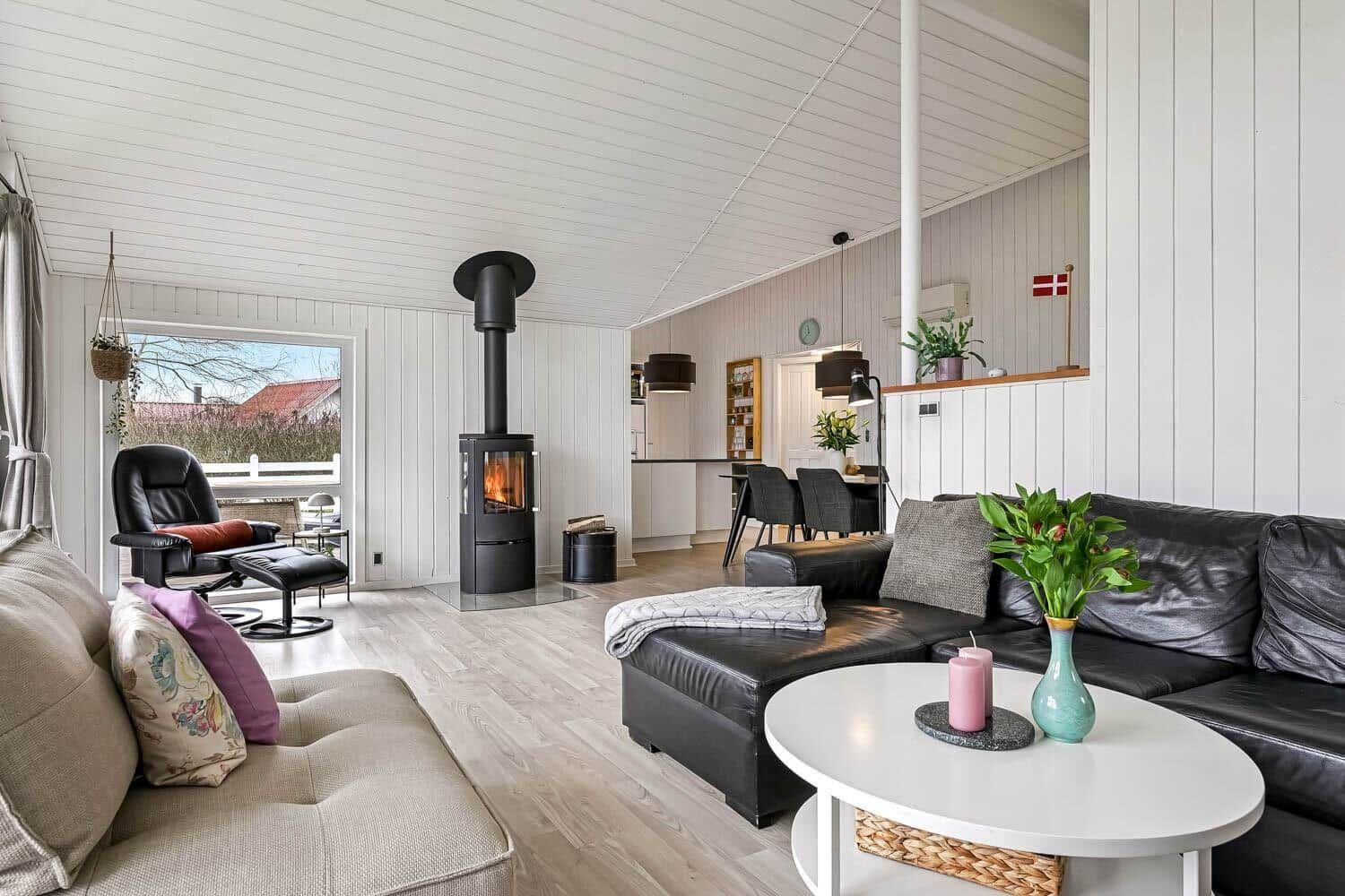 Wohnzimmer mit Kamin, Sofa und Esstisch im Hintergrund.
