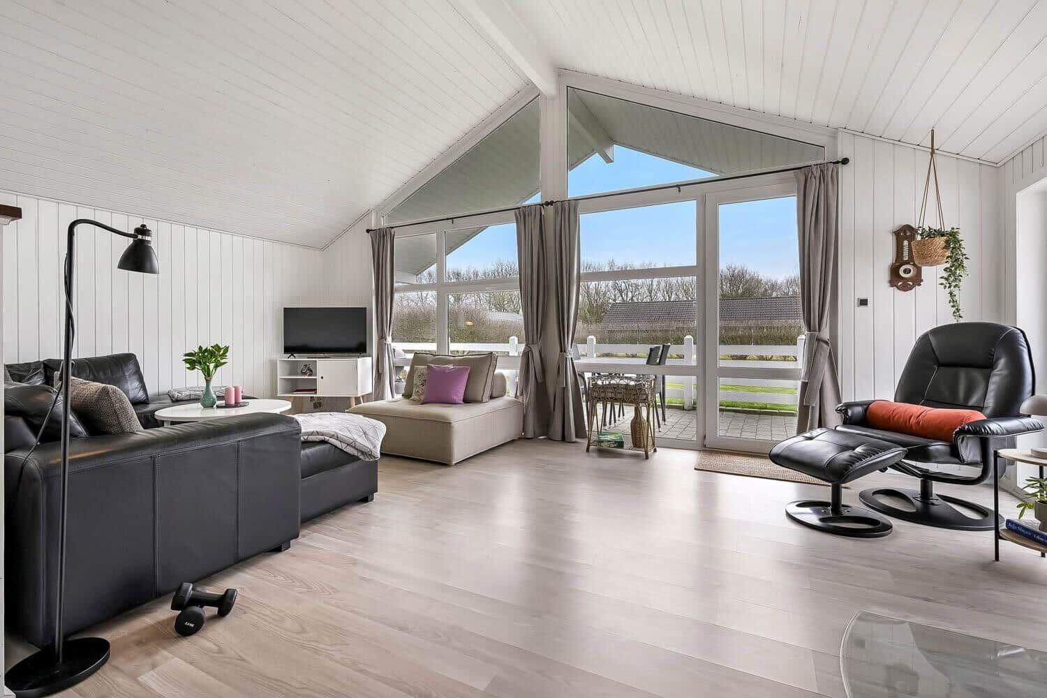 Großer Wohnbereich mit Schlafsofa, Fernseher und Blick auf die Terrasse.