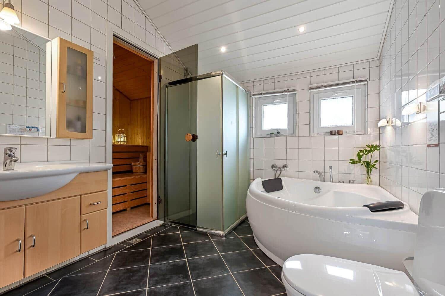 Badezimmer mit Badewanne, Dusche, Waschbecken und Sauna.