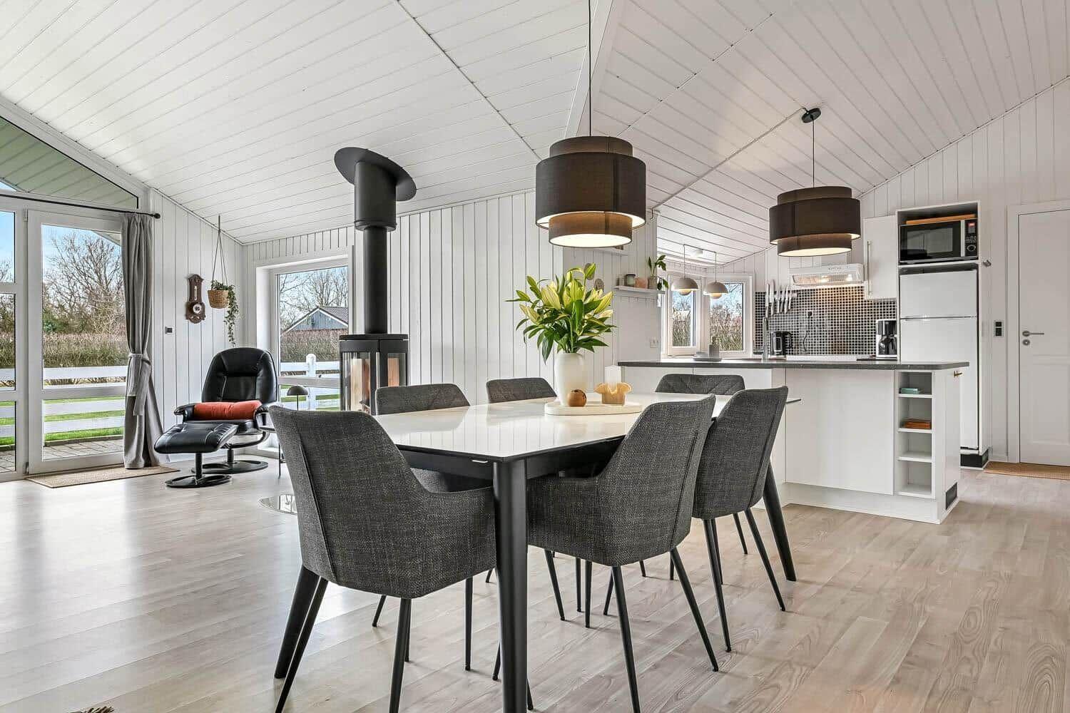 Moderne Küche mit Esstisch, schwarzer Kamin und weißen Wänden.