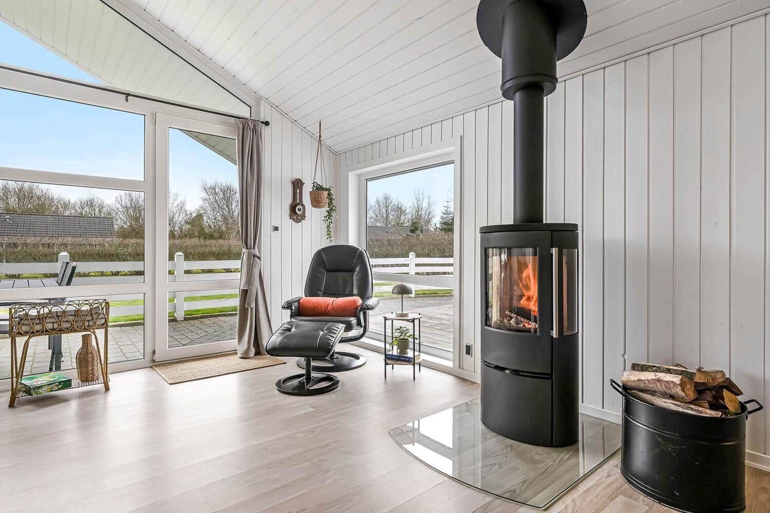Raum mit Kamin, Sessel und Blick auf Terrasse.