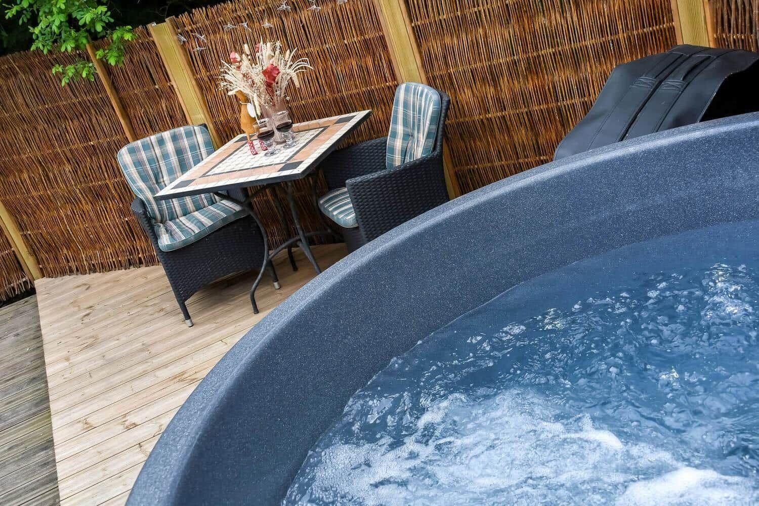 Hochwertiger Whirlpool mit Sitzbereich und Tisch auf Holzterrasse