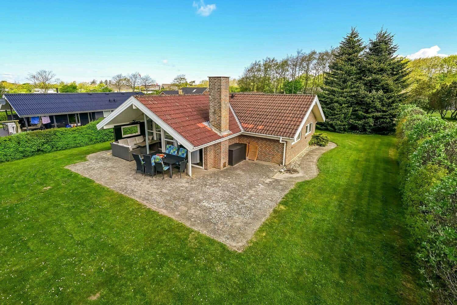 House with terrace, grill area, and garden. Red tiled roof and brick wall.