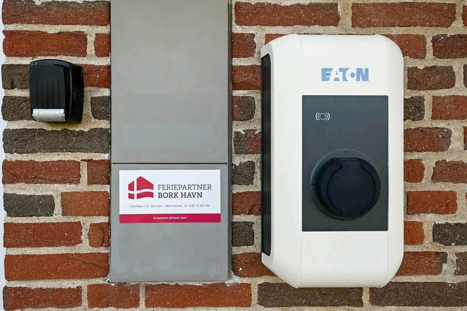 Charging station on a brick wall with sign from Feriepartner Bork Havn.