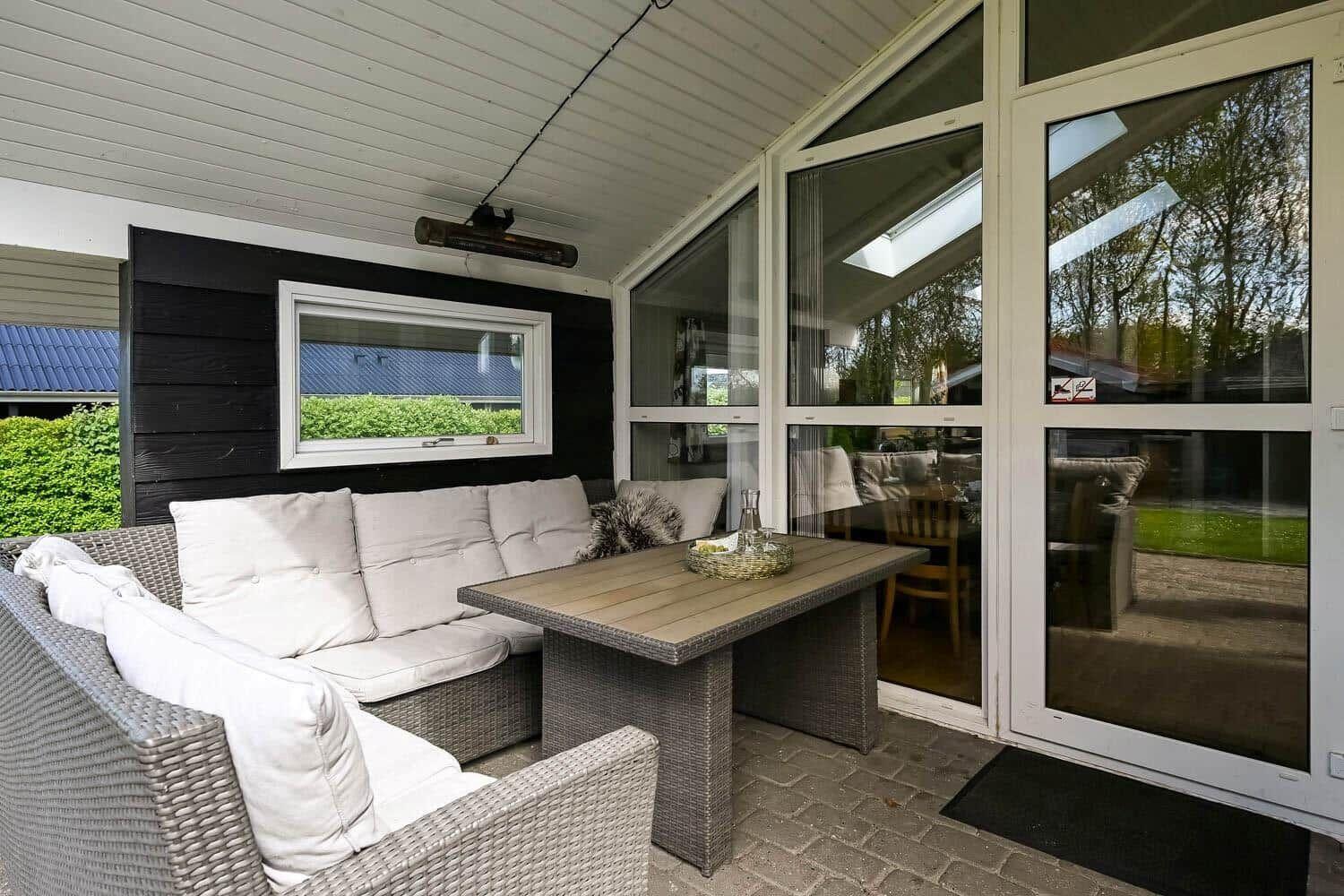 Terrace with seating group, table, and heater. Glass doors lead to the apartment.