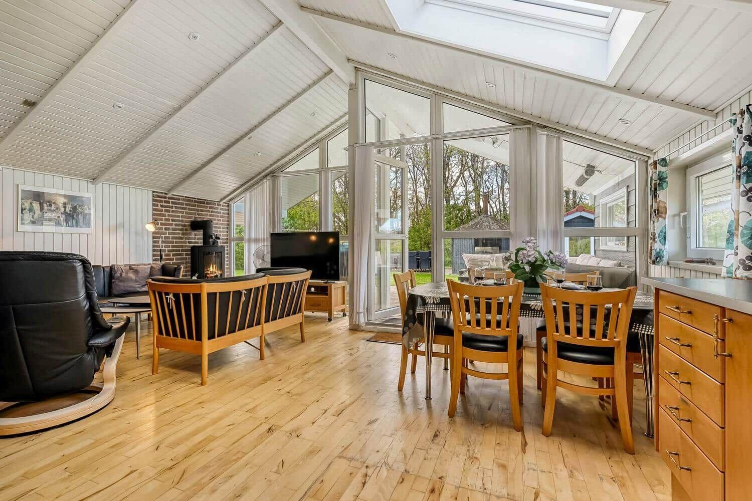 Living and dining area with wooden floor, large windows, and a fireplace.