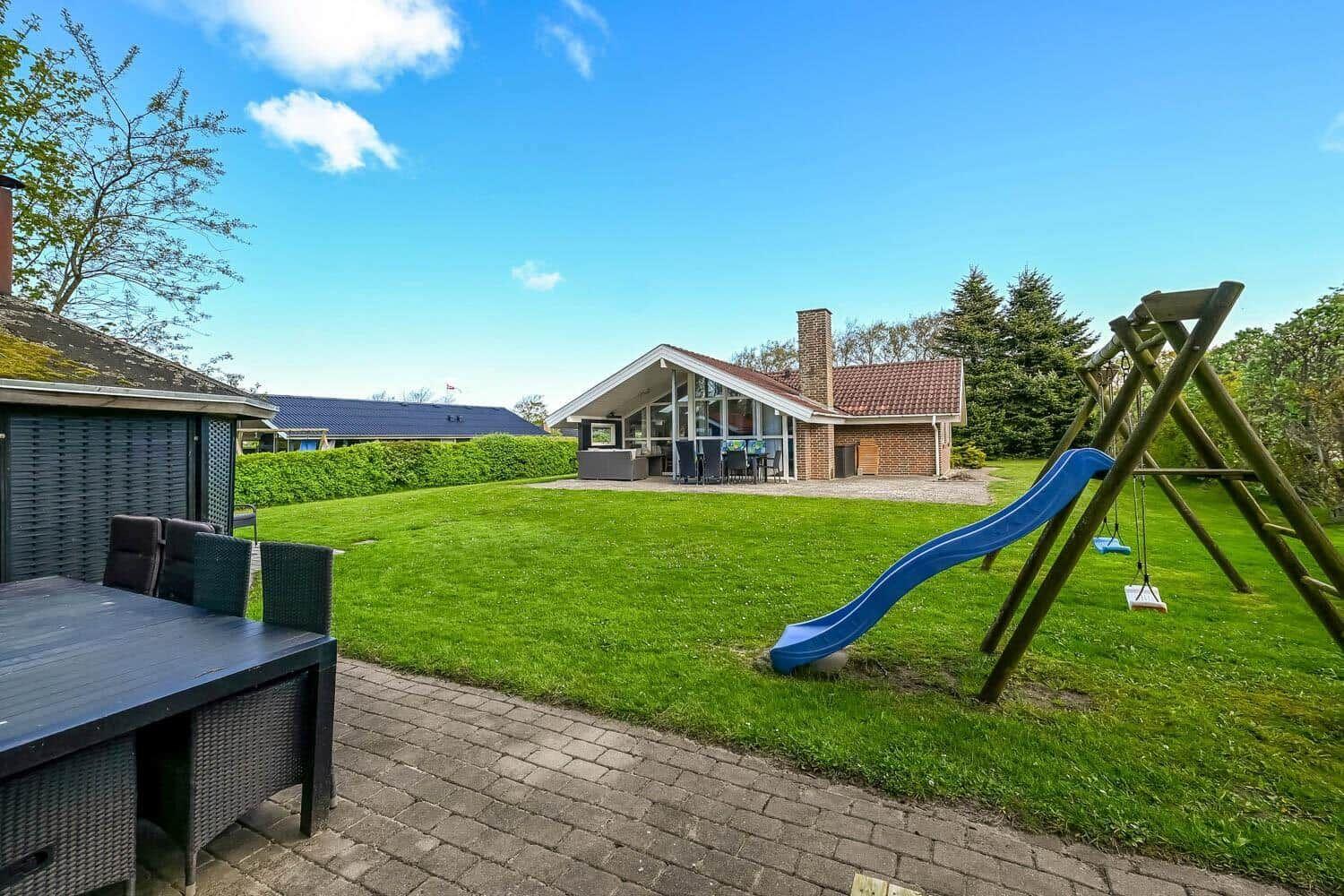 House with large garden, playground, and terrace with table and chairs.