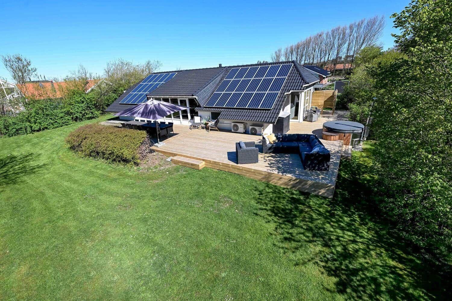 Haus mit Solaranlage, Holzterrasse, Garten und Whirlpool.