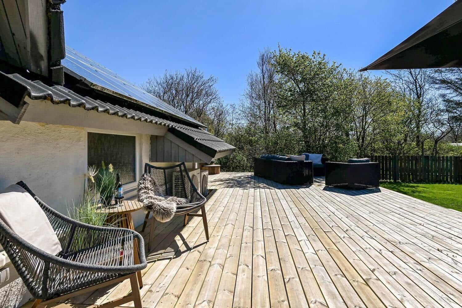 Holzterrasse mit Sitzgelegenheiten und Blick auf den Garten.