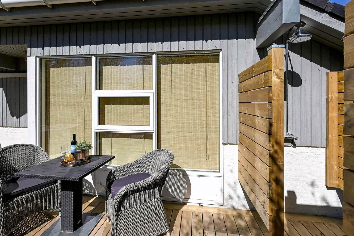 Terrasse mit Tisch, zwei Stühlen und Dusche im Freien.