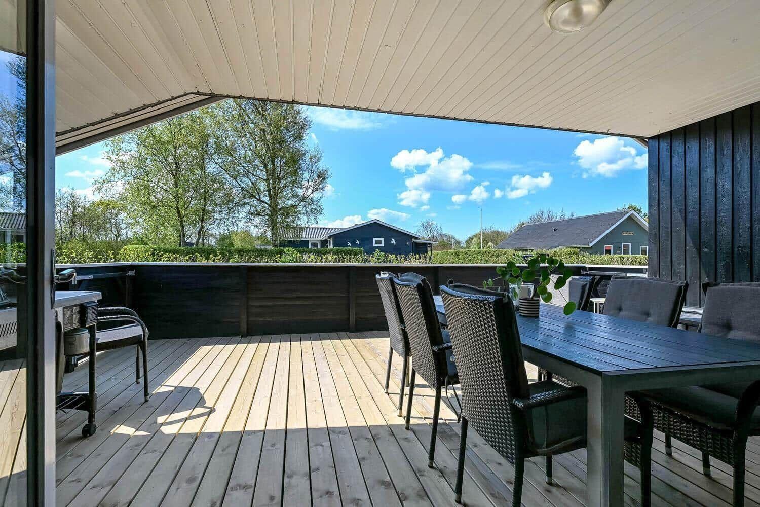 Terrasse mit Tisch und Stühlen, Blick auf grüne Landschaft und Häuser.