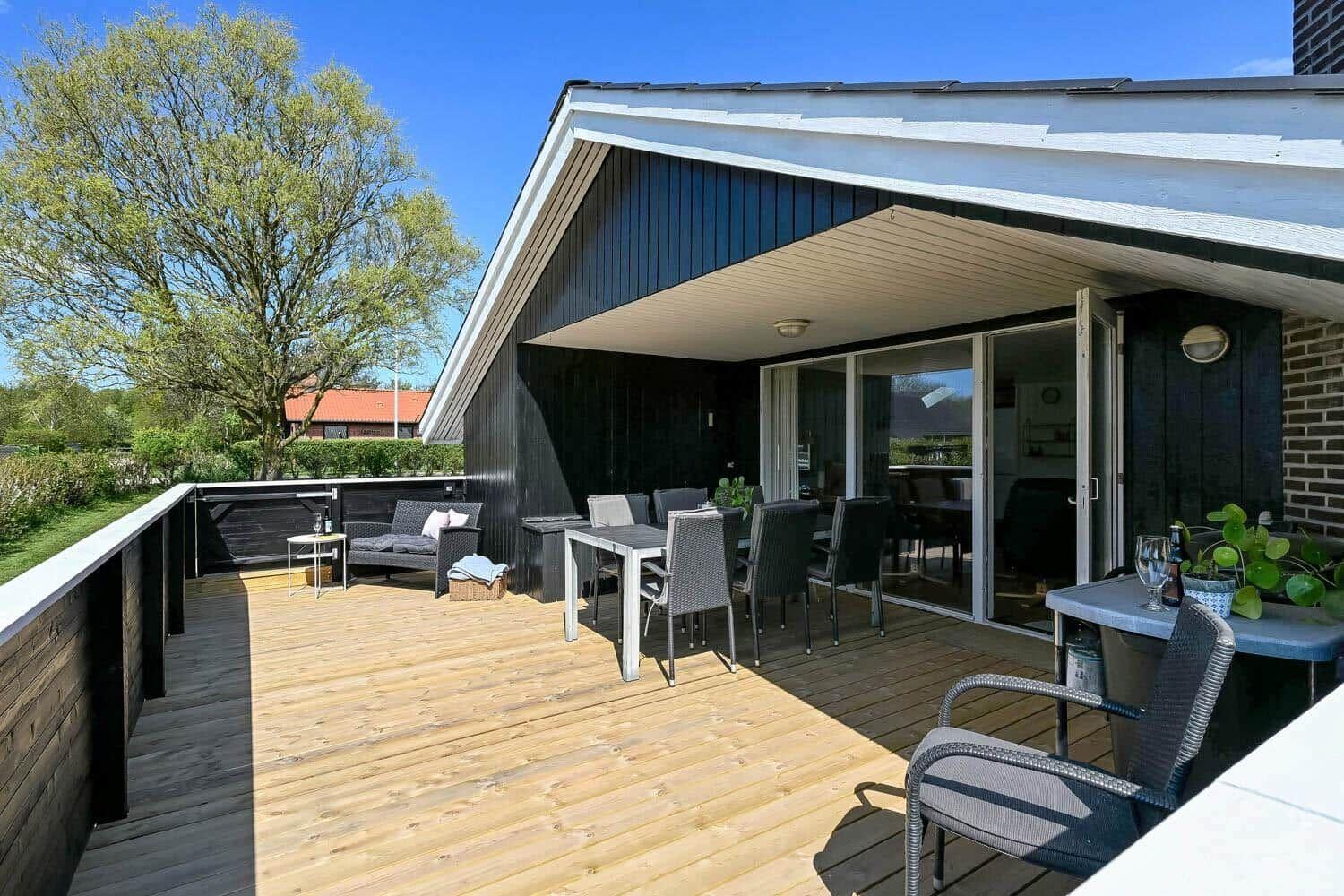 Terrasse mit Tisch, Stühlen und Sitzgelegenheit. Blick auf grüne Landschaft.
