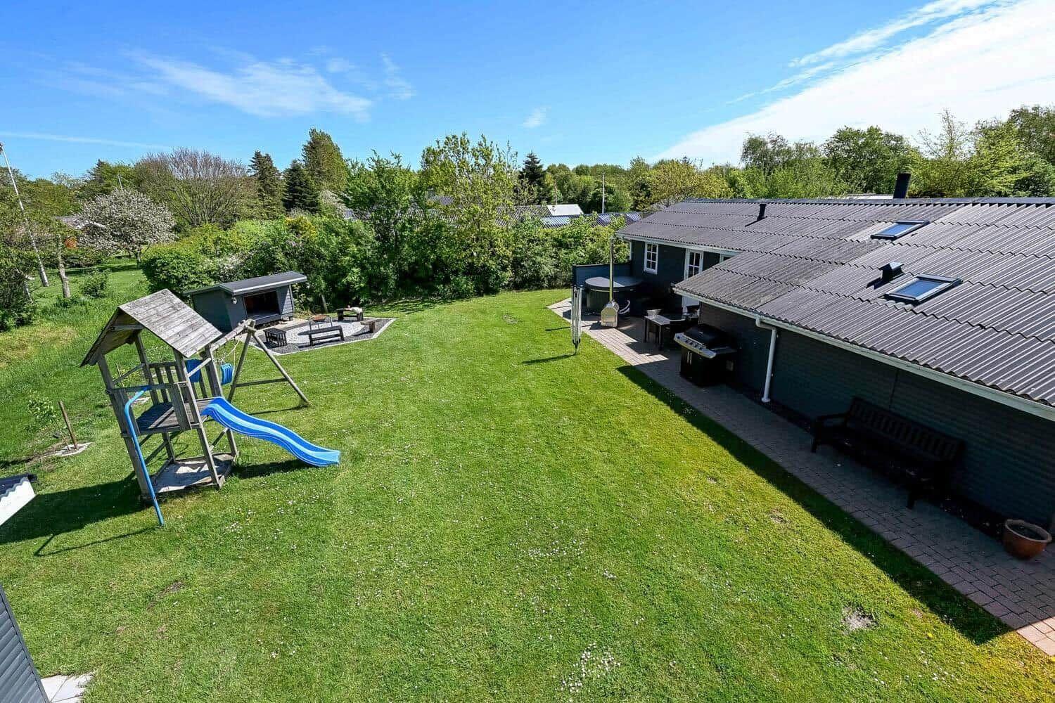 Großer Garten mit Spielplatz, Grill und Terrasse neben dem Haus.