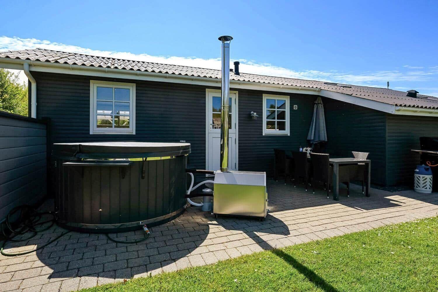 Haus mit Whirlpool, Terrasse und Sitzgelegenheiten im Freien.