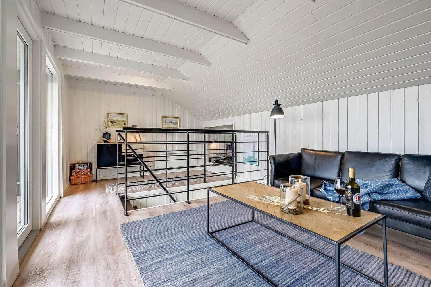 Wohnraum mit Sofa, Tisch und Treppe zur oberen Ebene.