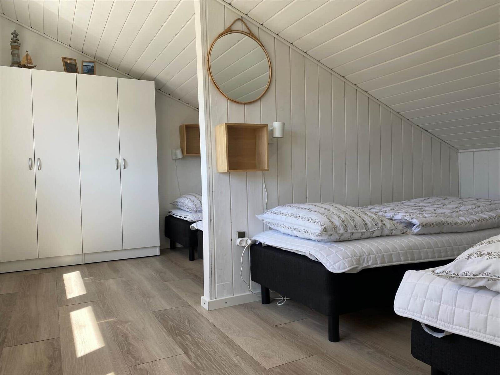 Zimmer mit zwei Betten, weißer Schrank und runden Spiegel an der Wand.