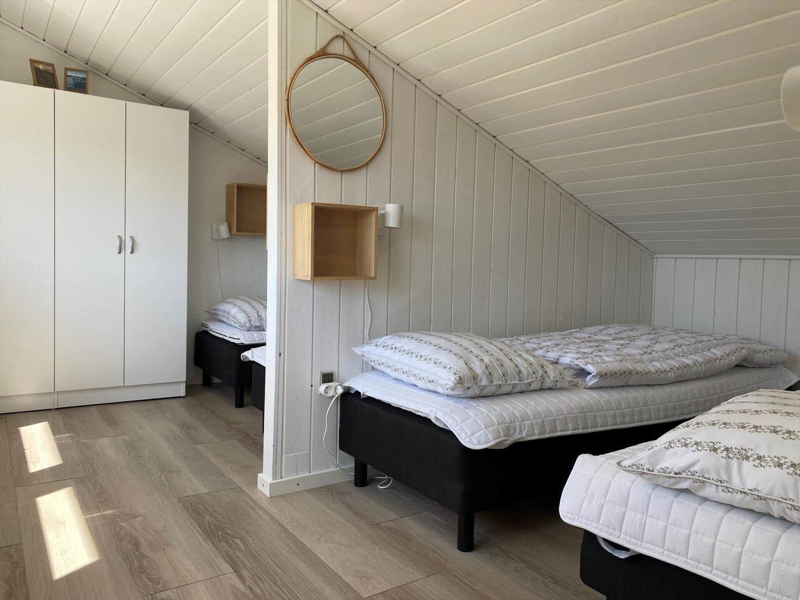 Zimmer mit zwei Betten, weißer Schrank und runden Spiegel an der Wand.