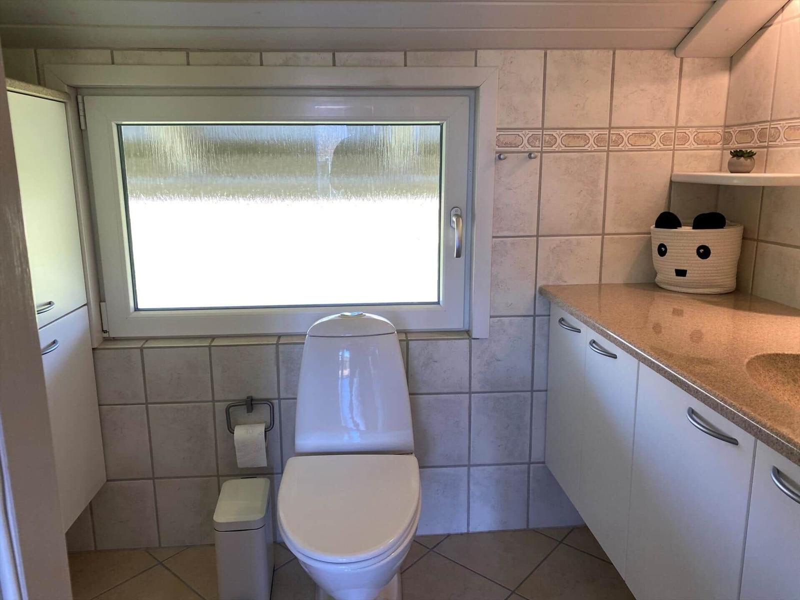 Bad mit Toilette, Fenster und Waschtisch mit Spüle.