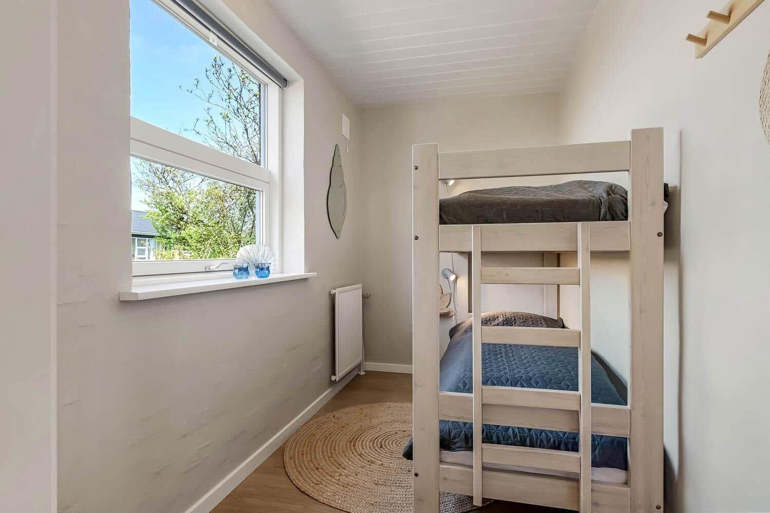 Zimmer mit Doppelstockbett, Fenster mit Blick auf Grün und Holzboden.