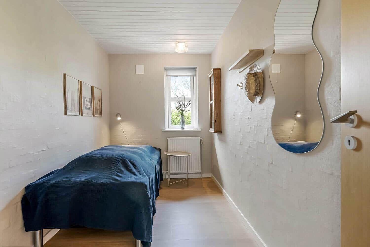 Schlafzimmer mit Bett, Fenster und Wandspiegel in Guitar-Form.
