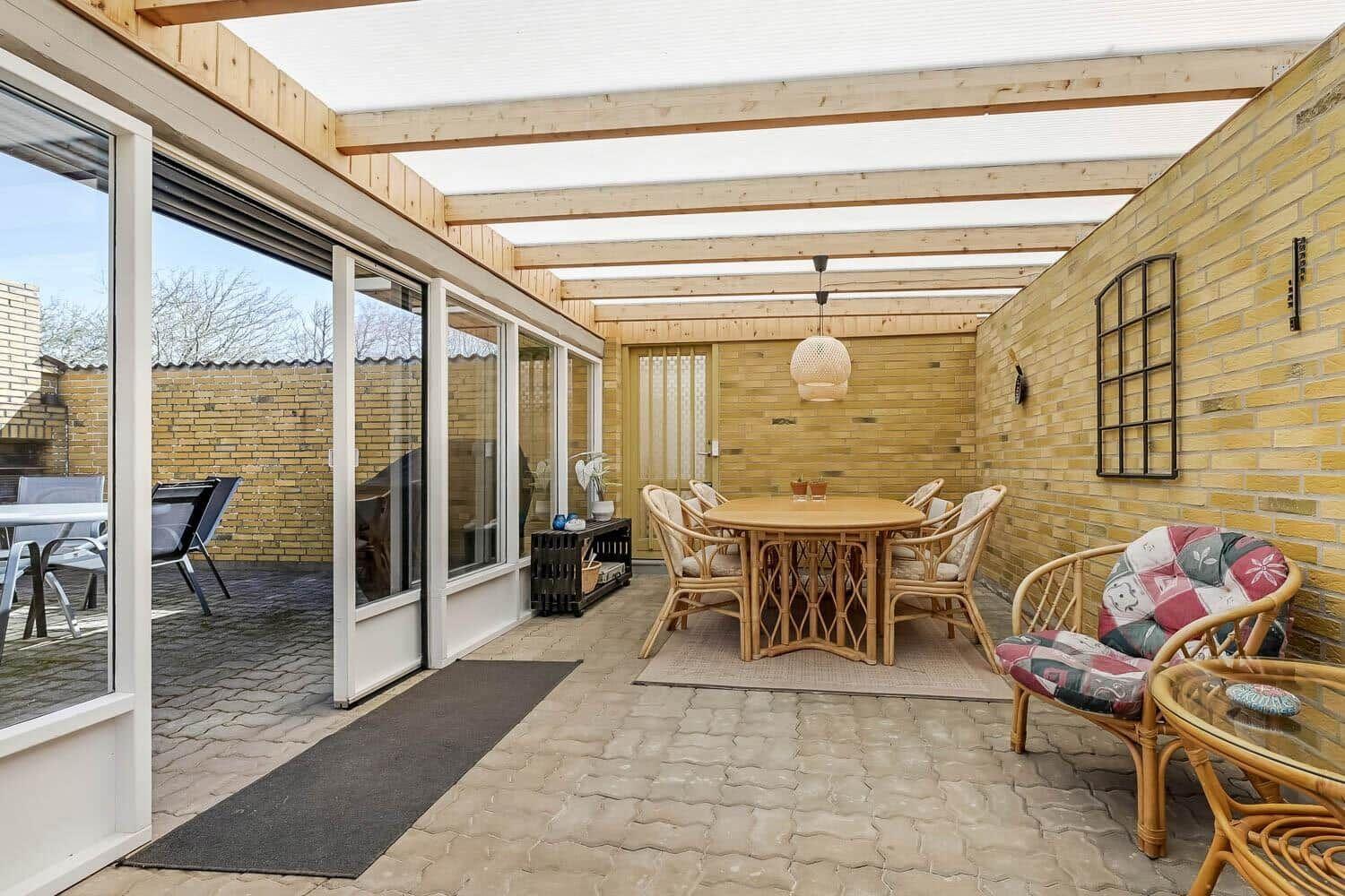 Terrasse mit Sitzgruppe, Tisch und Decke. Durchgehende Glaswände zur Wohnung.
