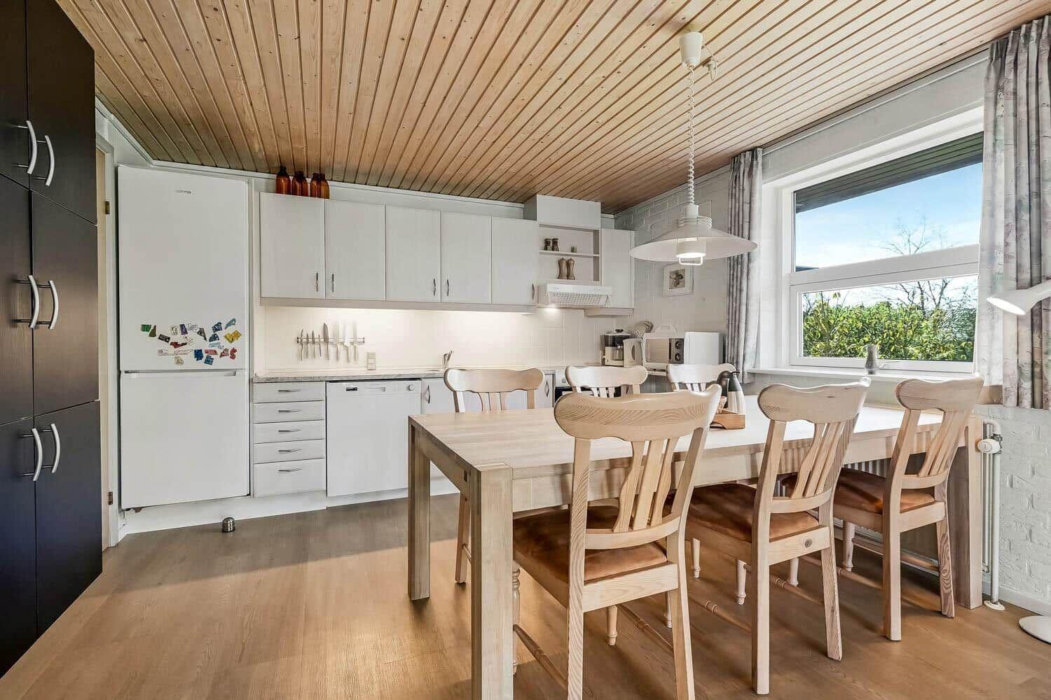 Küche mit Essbereich, Holztisch, Stühle und Fenster mit Blick auf Grün.