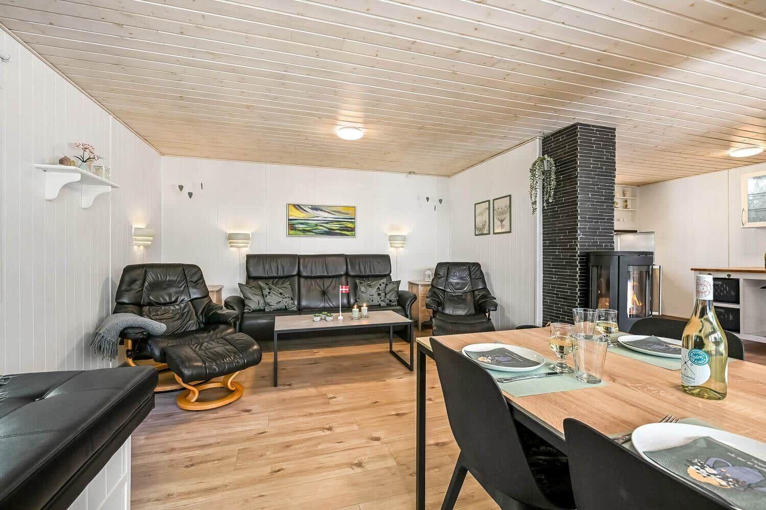 Wohn- und Essbereich mit Sofa, Sesseln, Esstisch und Kaminofen.