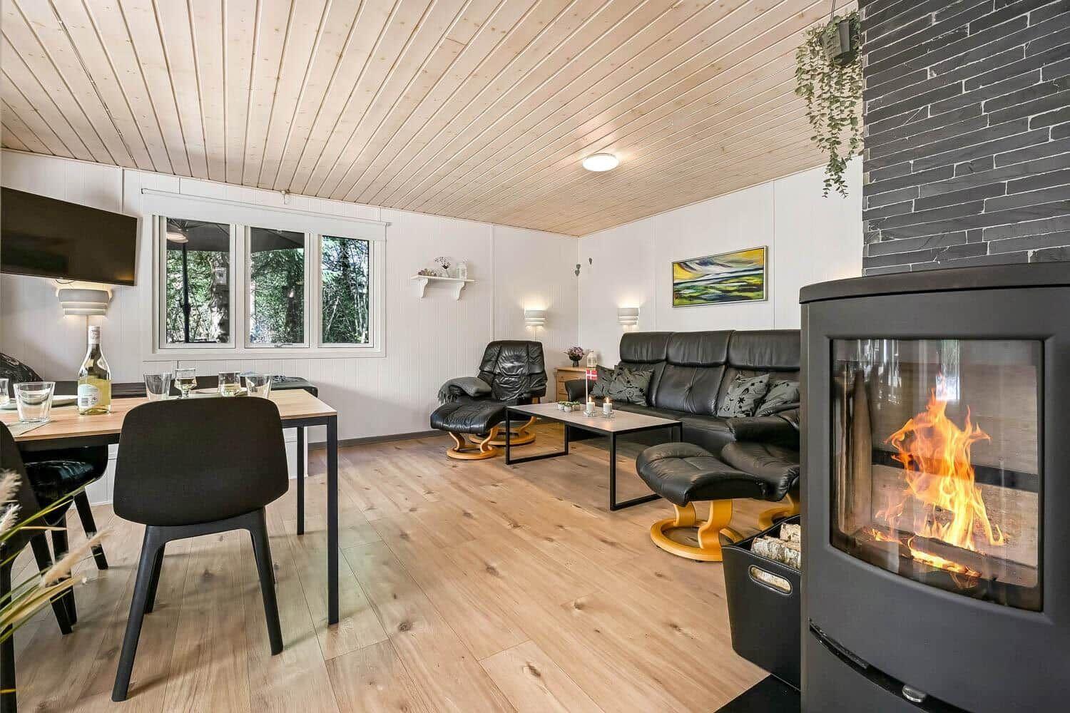 Wohn- und Essbereich mit Kamin, Sofa und Esstisch. Holzfußboden und Decke.