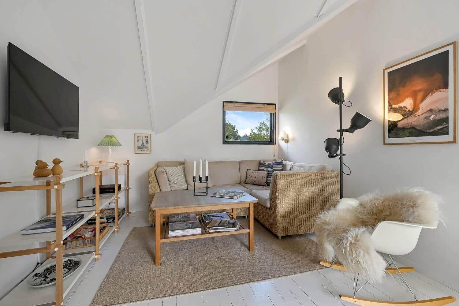 Wohnzimmer mit Sofa, Stehlampe, Fernseher und Fenster.