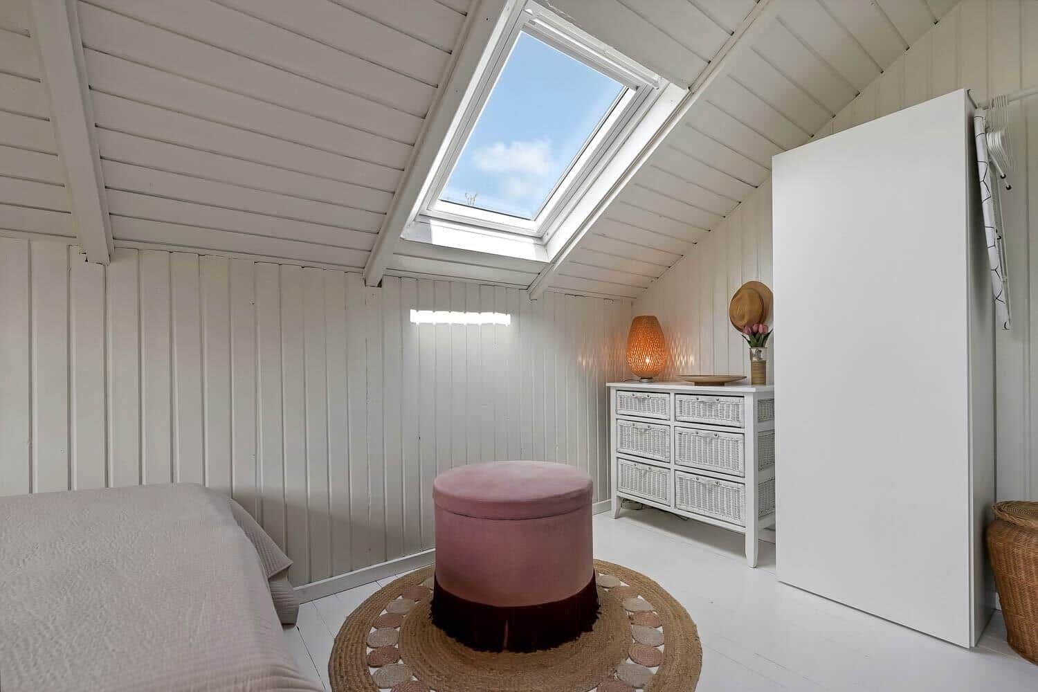 Schlafzimmer mit Dachfenster, Bett, Schrank und Wicker-Schrank.