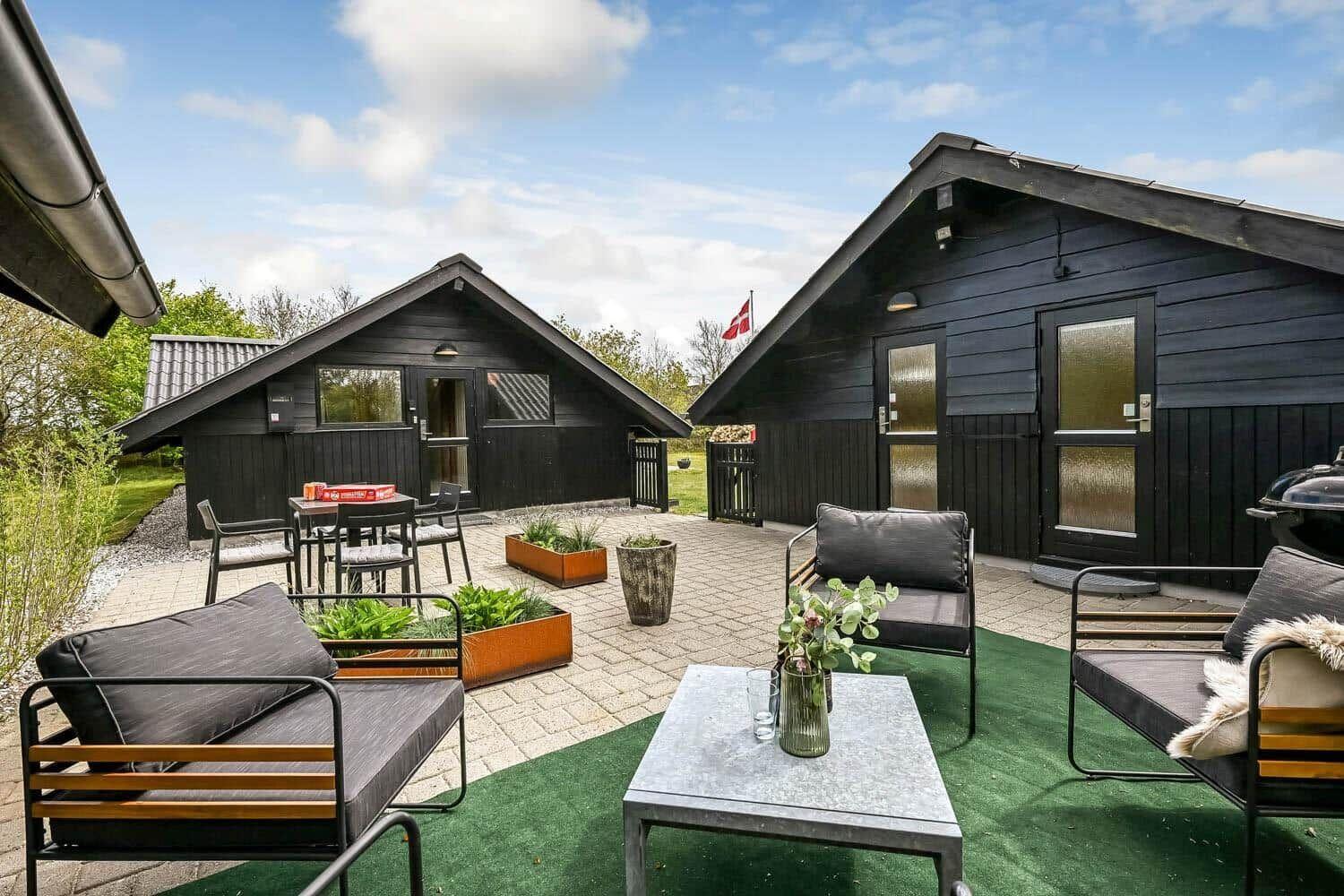 Terrasse mit Sitzgelegenheiten und zwei Holzhütten im Freien.