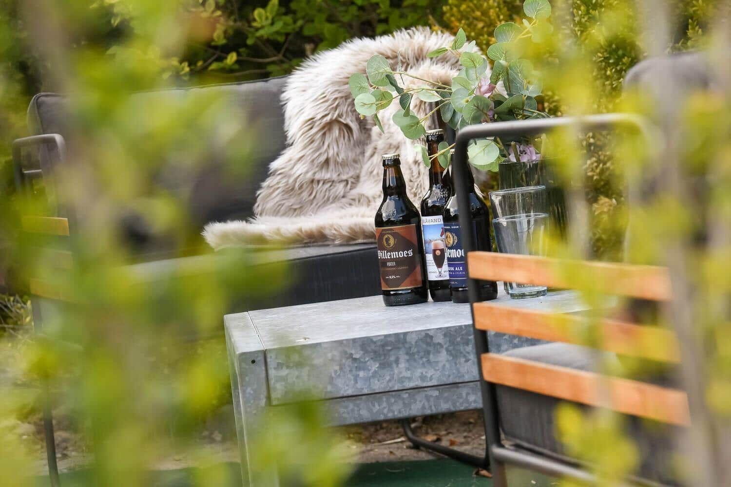 Außenbereich mit Sofa, Felldecke, Tisch und Bierflaschen.