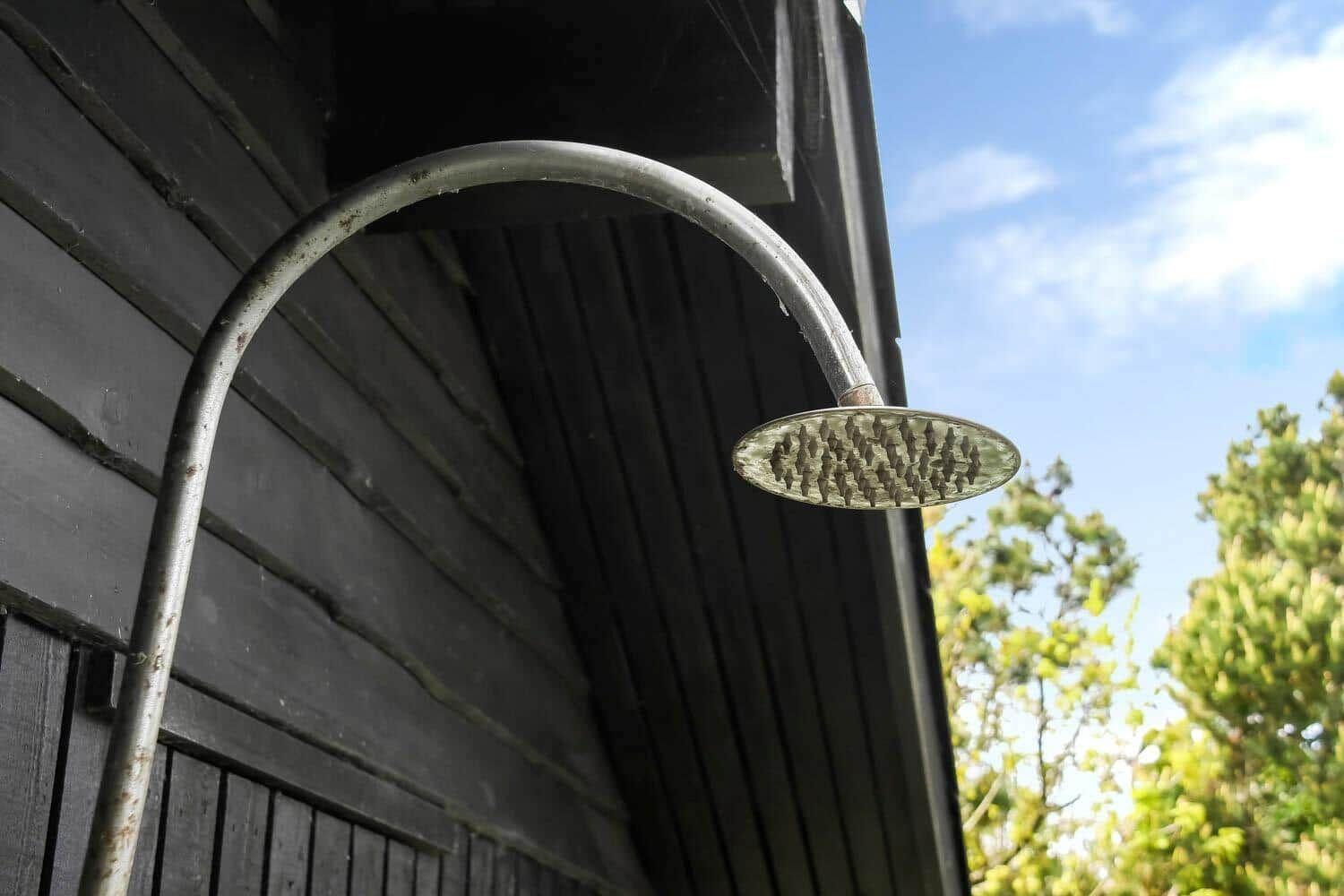 Außen-Dusche mit Regenbrause an der Wand eines Holzhauses.