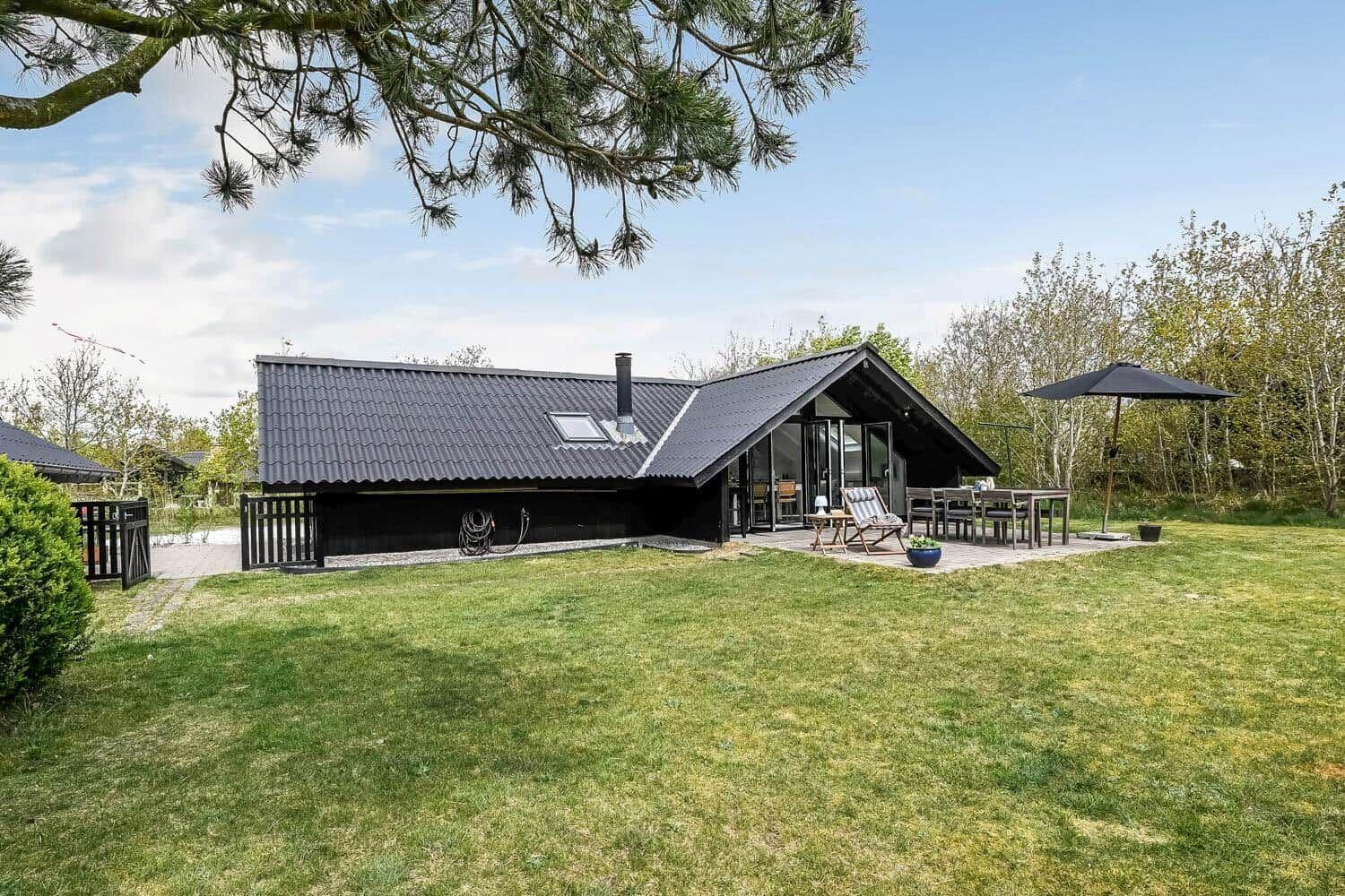 Moderne Villa mit Garten, Terrasse und Sitzgelegenheiten unter einem Baum.