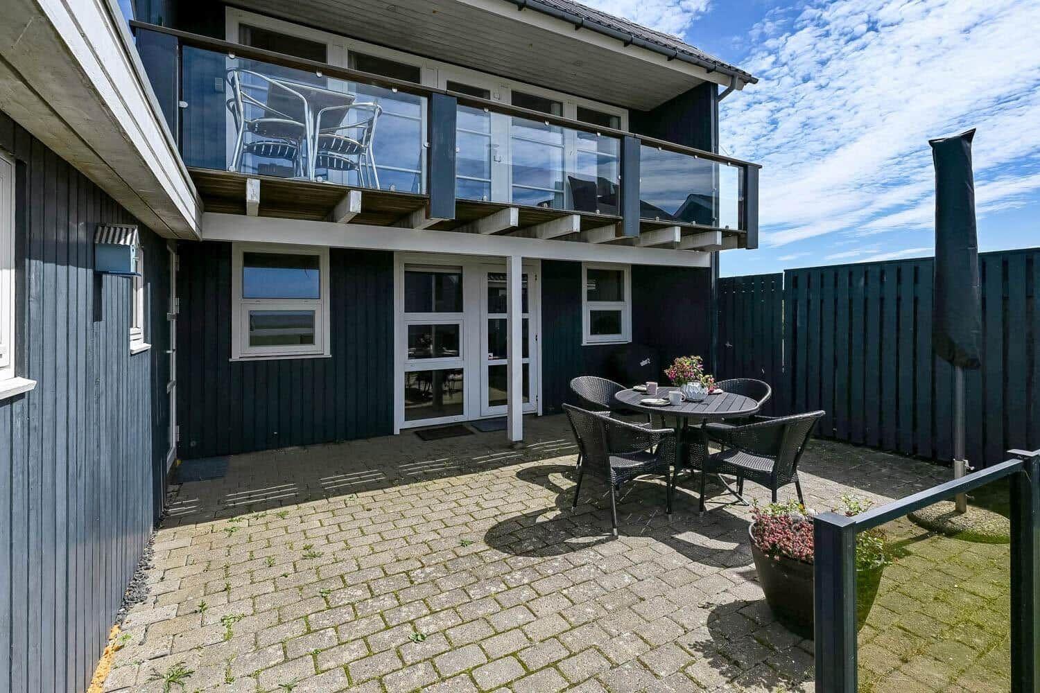 Terrasse mit Tisch und Stühlen vor einem Haus mit Balkon.