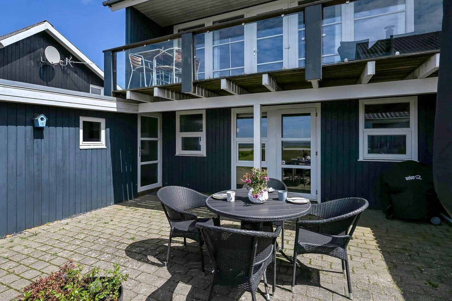Außenbereich mit Tisch und Stühlen vor einem Haus mit Balkon.